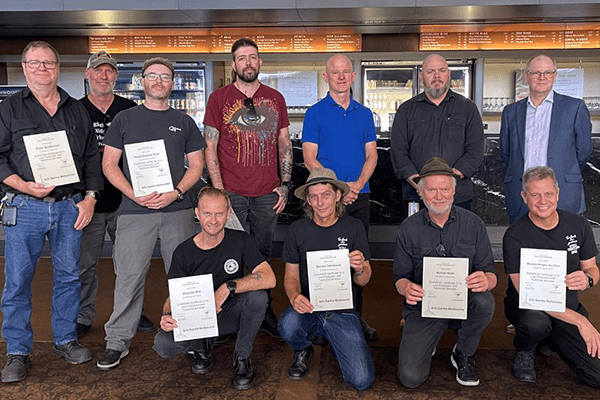Twelve people pose in one of QPAC's foyers. Some of the people hold certificates for their certification of Recognition of Prior Learning